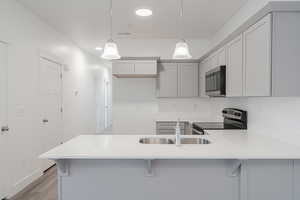 Kitchen with appliances with stainless steel finishes, light hardwood / wood-style flooring, kitchen peninsula, and hanging light fixtures