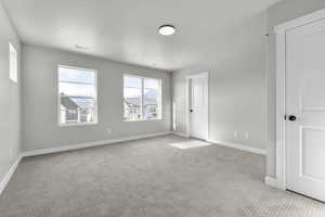 Unfurnished room featuring light carpet and a textured ceiling