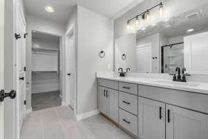 Bathroom featuring tile patterned flooring, vanity, and a shower with shower door