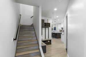 Stairs with light hardwood / wood-style floors and sink