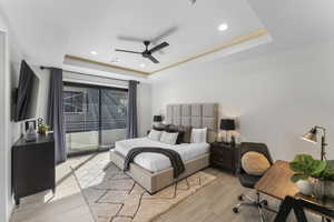 Bedroom with light wood-type flooring, access to outside, a raised ceiling, and ceiling fan