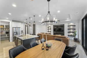 Dining room with built in shelves, sink, light wood-type flooring, and a tray ceiling