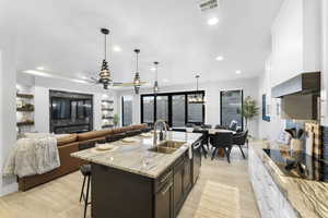 Kitchen with ceiling fan, a breakfast bar area, white cabinets, and dark brown cabinetry