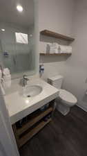 Bathroom featuring vanity, toilet, a tile shower, and hardwood / wood-style floors