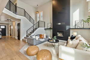 Living room featuring a towering ceiling, light wood-type flooring, a large fireplace, and a wealth of natural light