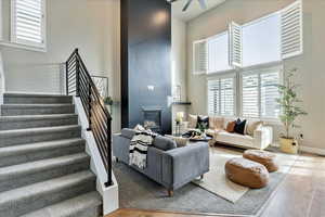 Living room with wood-type flooring, ceiling fan, and a high ceiling