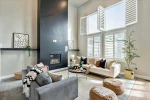 Living room with a fireplace, carpet, and a towering ceiling