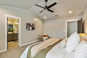 Carpeted bedroom featuring ensuite bathroom, ceiling fan, and lofted ceiling