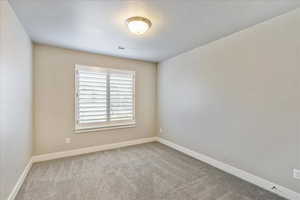 Carpeted spare room featuring a textured ceiling