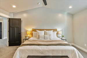 Carpeted bedroom with ceiling fan and vaulted ceiling