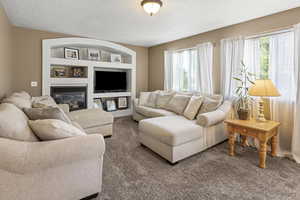 Living room with updated carpet, built in entertainment shelving, and bright windows