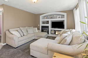 Living room with updated carpet, built in entertainment shelving, and bright windows