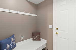 Mud room with bench, hooks, and access to garage