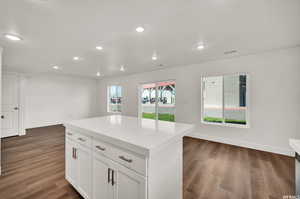 Kitchen with dark hardwood / wood-style flooring, a center island, and white cabinets