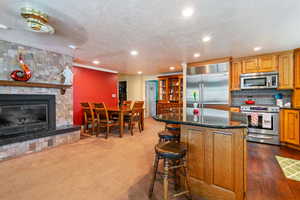 Kitchen with dark stone countertops, a kitchen island, carpet floors, stainless steel appliances, and a fireplace