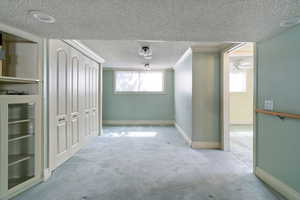 Unfurnished room featuring crown molding, carpet, and a textured ceiling