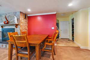 Carpeted dining room featuring a fireplace, ornamental molding, and a textured ceiling