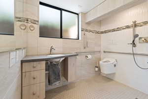 Bathroom with tiled shower, toilet, tile patterned floors, and tile walls