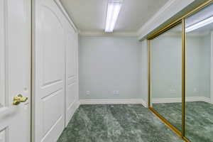 Unfurnished bedroom featuring dark colored carpet and ornamental molding