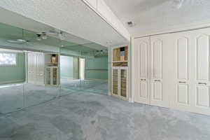 Unfurnished bedroom with ceiling fan, two closets, and a textured ceiling