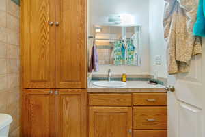 Bathroom with vanity, tile walls, and toilet