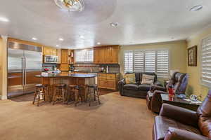 Carpeted living room featuring ornamental molding, sink, and a textured ceiling