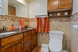 Bathroom featuring tile patterned flooring, tile walls, backsplash, and double sink vanity