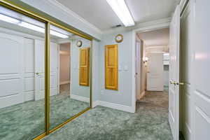 Hall featuring crown molding, a textured ceiling, and carpet flooring