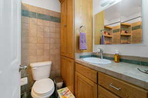 Bathroom featuring vanity, toilet, and tile walls