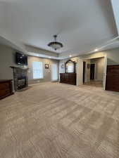 Master Bedroom featuring a fireplace, light carpet, and a raised ceiling