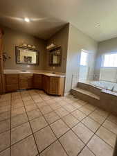 Bathroom featuring a relaxing jetted tub, dual vanity, and tile patterned floors