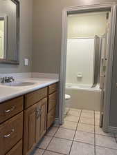 Full bathroom featuring vanity, shower / bath combination with jetted tub, toilet, and tile patterned floors