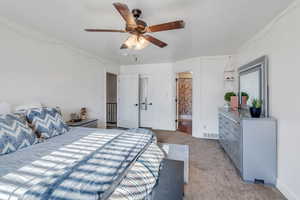 Carpeted bedroom with ensuite bath and ceiling fan