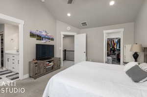 Carpeted bedroom with a closet, vaulted ceiling, ensuite bath, sink, and a walk in closet