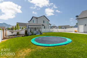 Rear view of property featuring a trampoline and a yard