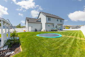 Back of house featuring a lawn and a trampoline