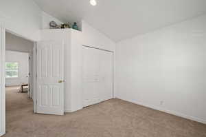 Unfurnished bedroom featuring carpet floors, a closet, and lofted ceiling