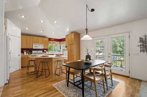 Dining area featuring vaulted ceiling, french doors, and light wood-type flooring