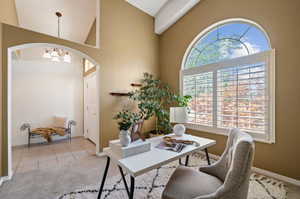 Home office featuring light tile patterned floors, high vaulted ceiling, and a chandelier