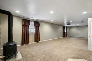 Unfurnished living room featuring a textured ceiling, light carpet, and a wood stove