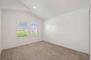 Empty room featuring carpet floors and lofted ceiling