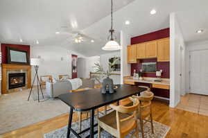 Carpeted dining area with ceiling fan and vaulted ceiling