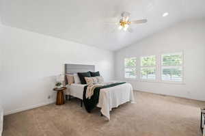 Carpeted bedroom with ceiling fan and lofted ceiling