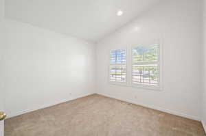 Unfurnished room with light carpet and vaulted ceiling