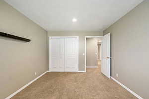 Unfurnished bedroom with a textured ceiling, a closet, and light colored carpet