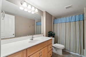 Bathroom with vanity, tile patterned floors, a textured ceiling, and toilet