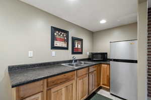 Kitchen featuring light tile patterned flooring, stainless steel fridge, and sink