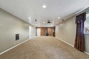 Unfurnished living room with a wood stove, brick wall, and carpet floors