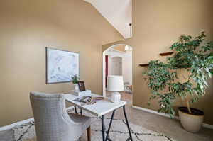 Carpeted home office with high vaulted ceiling