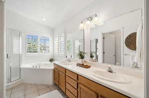 Bathroom featuring a textured ceiling, dual bowl vanity, tile patterned floors, separate shower and tub, and vaulted ceiling